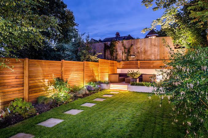 Garten mit beleuchtetem Holzzaun und Sitzbereich